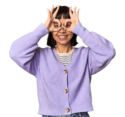 Young Hispanic woman with short black hair in studio showing okay sign over eyes