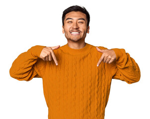 Young Chinese man in studio background points down with fingers, positive feeling.