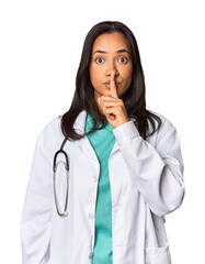 Wall Mural - Young Filipina doctor with stethoscope in studio keeping a secret or asking for silence.