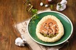 Mazurek, Polish Easter sweet made from shortcrust pastry in the shape of an egg with Easter decoration on a green plate on a wooden background. Polish cuisine.