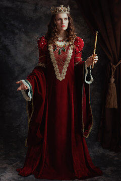 Full length portrait of medieval queen in red dress with wand