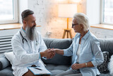 Fototapeta  - Senior male doctor examining his patient mature attractive woman during home or clinic visit. Healthcare for elderly retired people, insurance. Illness, disease diagnosis, treatment prescription