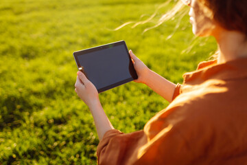 Fototapete - Smart agriculture. A young woman farmer wearing glasses holds a tablet on a green wheat field. A woman agronomist checks the quality of the crop using a digital tablet. Agriculture concept.