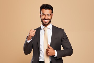 Wall Mural - Smiling arab businessman with thumbs up over beige background