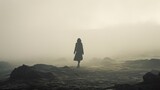 Fototapeta  -  a person standing in the middle of a field on a foggy day with their back turned to the camera.