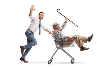 Sticker - Cheerful young businessman running and pushing a senior man in a shopping cart