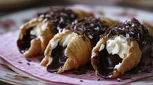  A Plate Topped With Chocolate Covered Pastries On Top Of A Pink And White Polka Dot Covered Plate With White And Brown Sprinkles.