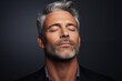 © Pierre - Studio portrait of handsome mature man with eyes closed, charcoal colored background.