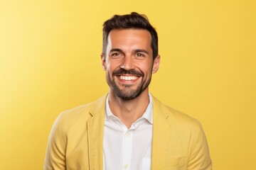 Wall Mural - Portrait of a happy young man smiling and looking at camera on yellow background