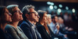 © tashechka - A group of attentive adults sit in an audience, focusing on a presentation at a conference or seminar.