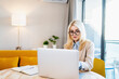 © DedMityay - Young woman working at table on laptop in home office, distance work concept.