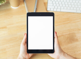 Sticker - Hands holding digital tablet with mockup of blank screen on desk in office room.