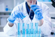 © Supapich - Woman research scientist biology chemistry medicine pouring liquid from beaker to test tube indoor science laboratory room, adult female person blue glove work discovery experiment medical chemist