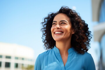 Wall Mural - smiling woman in blue shirt over blue sky and city outdoor background