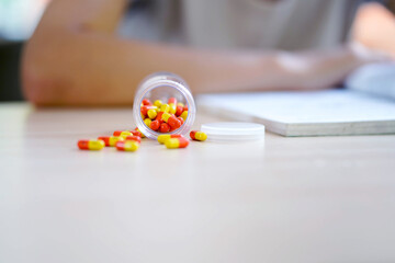 Closeup the medicine bottle spilled on table and blurred of student background.