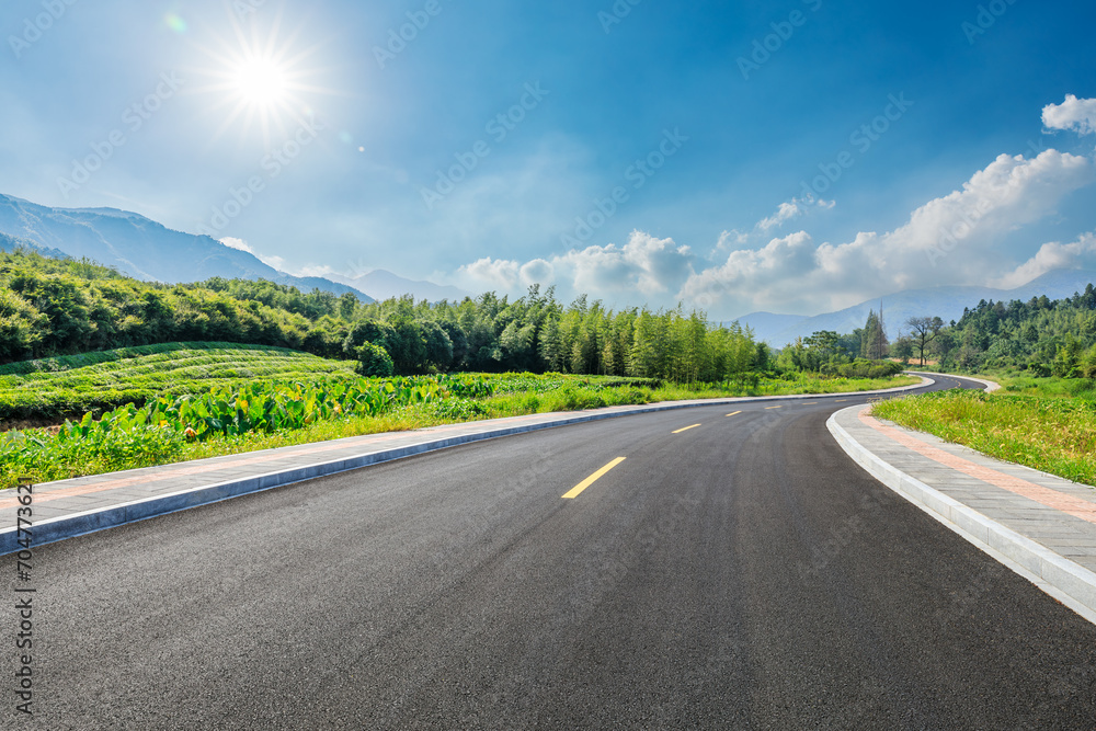 Country road and green forest with mountain natural landscape on a sunny day