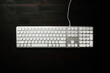 Top view of white computer keyboard on black office desk