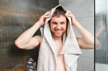 Man with wet hair hold towel after shower. Morning washing, wake up, everyday life. Refreshment, healthcare. Hygiene, sexy guy wash, spa, relax. Man in bathroom with muscular body on grey background