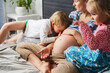 © Westend61 - Pregnant mother with children on bed at home