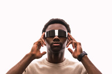 Cool young man wearing cyber glasses against white background putting fingers on temples