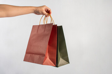 Red and green paper shopping bag in hand on white background.