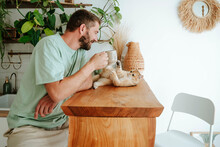 Man playing with cat on wooden table at home