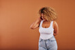 © Flamingo Images - Laughing woman in a tank top and jeans posing on an orange background