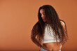 © Flamingo Images - Young black woman looking sideways against an orange background