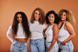 © Flamingo Images - Diverse women in jeans and white tops smiling on an orange background