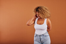 Laughing Woman In A Tank Top And Jeans Posing On An Orange Background
