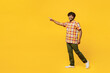Full body side view smiling happy young Indian man he wears shirt casual clothes walking going point finger aside on area isolated on plain yellow color background studio portrait. Lifestyle concept.