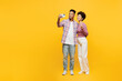 © ViDi Studio - Full body young couple two friend family man woman wear purple casual clothes together do selfie shot on mobile cell phone post photo on social network show v-sign isolated on plain yellow background