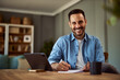 © Jelena - Portrait of a cheerful adult male freelancer writing notes on a sheet of paper while sitting in front of a tablet.