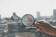 Hand holding a magnifying glass to check the air quality for PM 2.5 over smog city from PM2.5 dust on background low visibility city with dangerous haze and fog. health care, pm 2.5 warning