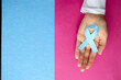Blue ribbon in support of trafficking and sexual slavery. Blue ribbon on female hands on a blue background