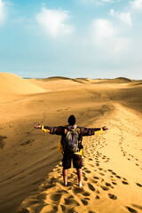 Standing man back view open arms and enjoy with wild beautiful desert in front - lifestyle and adventure trekking backpack travel vacation people concept - alternative summer holiday trip for people