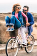 © simona - Joyful love friendship concept - happy adult caucasian, couple having fun with bicycle in outdoor leisure activity. concept of active playful people with bike during vacation - everyday joy lifestyle