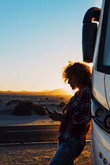 Wall Mural - People on travel with modern camper. Woman using mobile phone roaming against big motorhome. Concept of modern lifestyle and travelers. Vacation and vanlife sending message with cellular. Everywhere 