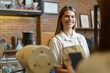 © DG PhotoStock - Portrait of happy beautiful female coffee shop employee standing behind the counter bar and serving a coffee cup to female unrecognizable client.