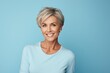 Beautiful middle aged woman with short hair posing over blue background.