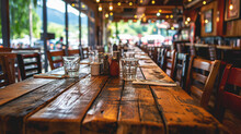 Long Wooden Table With Glasses And Condiments, Lined With Chairs, In A Restaurant With A Cozy, Inviting Atmosphere