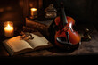 © pilipphoto - Old violin at the table with books and candles, still life