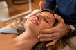© Lomb - A woman enjoys a craniosacral therapy session, experiencing relaxation with a gentle head massage.