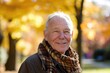 © furyon - A senior man with a warm smile, standing in a park during autumn, surrounded by fall foliage.