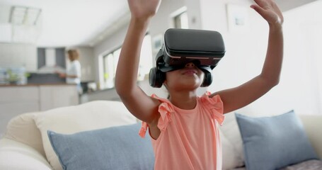 Wall Mural - happy biracial girl wearing vr headset using virtual interface at home, copy space, slow motion