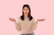 © Iryna - Young Indian woman in wool winter sweater showing both hands open palms, presenting and advertising comparison and balance on pink background
