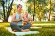 Mental and spiritual health concept. Elderly married couple holding hands in namaste while doing yoga on fresh air. Caucasian man and woman sitting on mats in lotus position and keeping eyes closed.