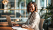 © Studio Nova - Woman smiling while working on a laptop in a bright and modern office environment