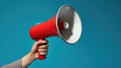 Person's hand holding a red and white megaphone against a teal blue background.