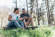 © BalanceFormCreative - Sitting on a fallen tree trunk, the couple, including the determined overweight female, catch their breath, their laughter blending with the rustling leaves as they enjoy a post-workout moment.
